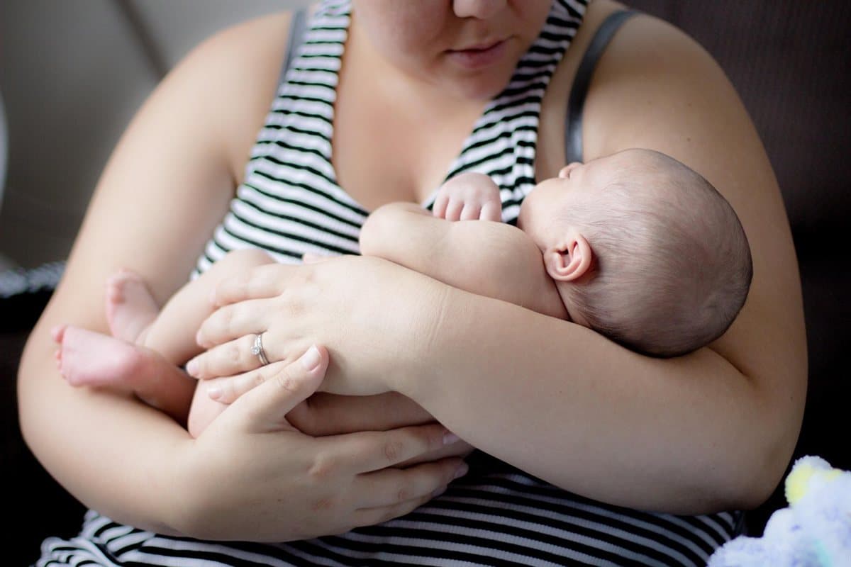 Maman tenant son nouveau-né dans ses bras : trouver un praticien formé pour une frénectomie